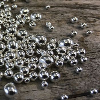 silver casting grain on a dark wooden backgroud